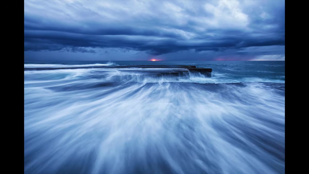 Photographer aiming camera inland away from the ocean