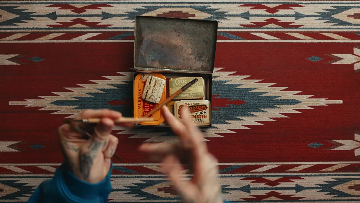 Two short-handled watercolor brushes laid inside the open tin