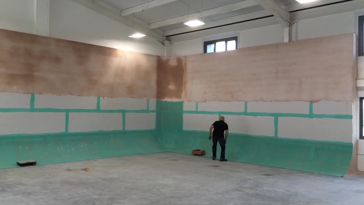 Plasterer applying top coat to upper section with scaffold in place