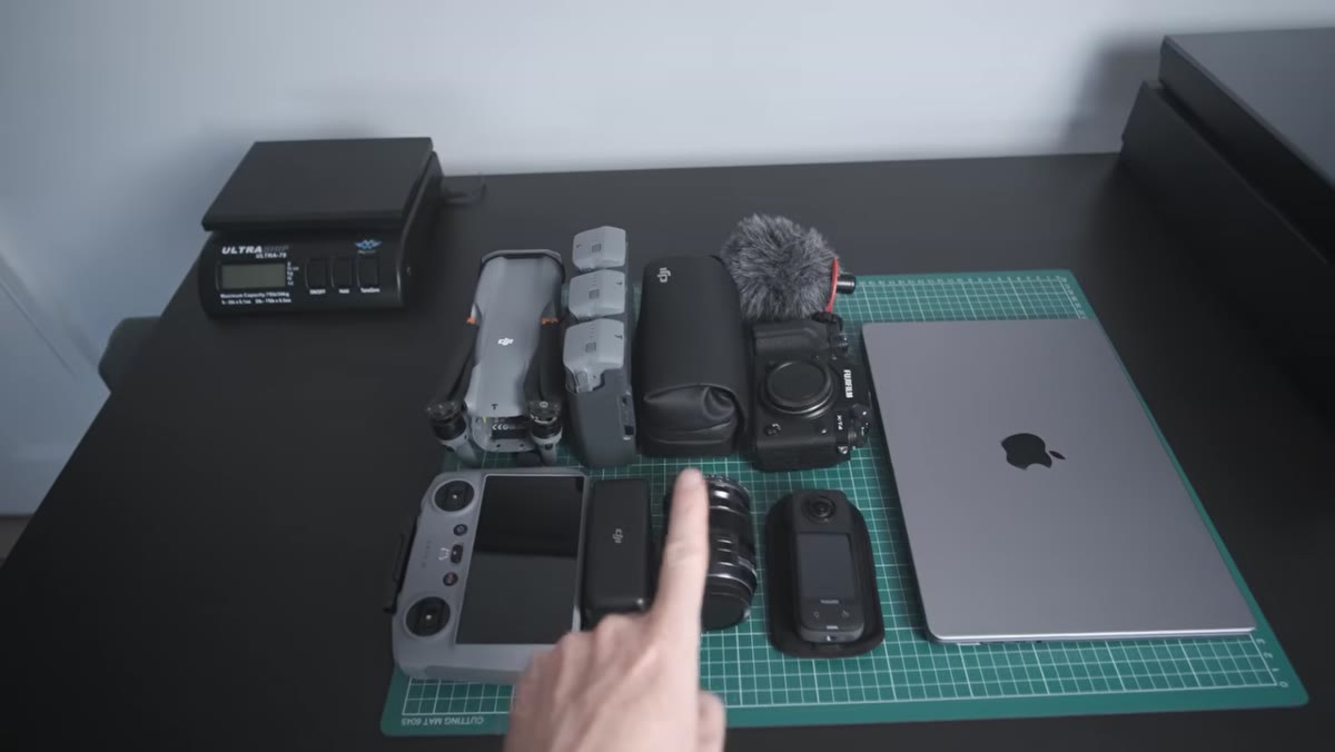 Video equipment laid out including drone controller, wireless mics, and compact cameras