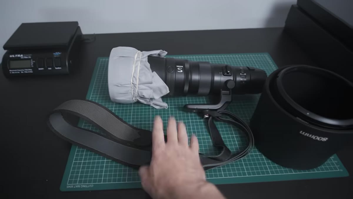 Large 800mm lens attached to a shoulder strap, worn separately from the camera bag