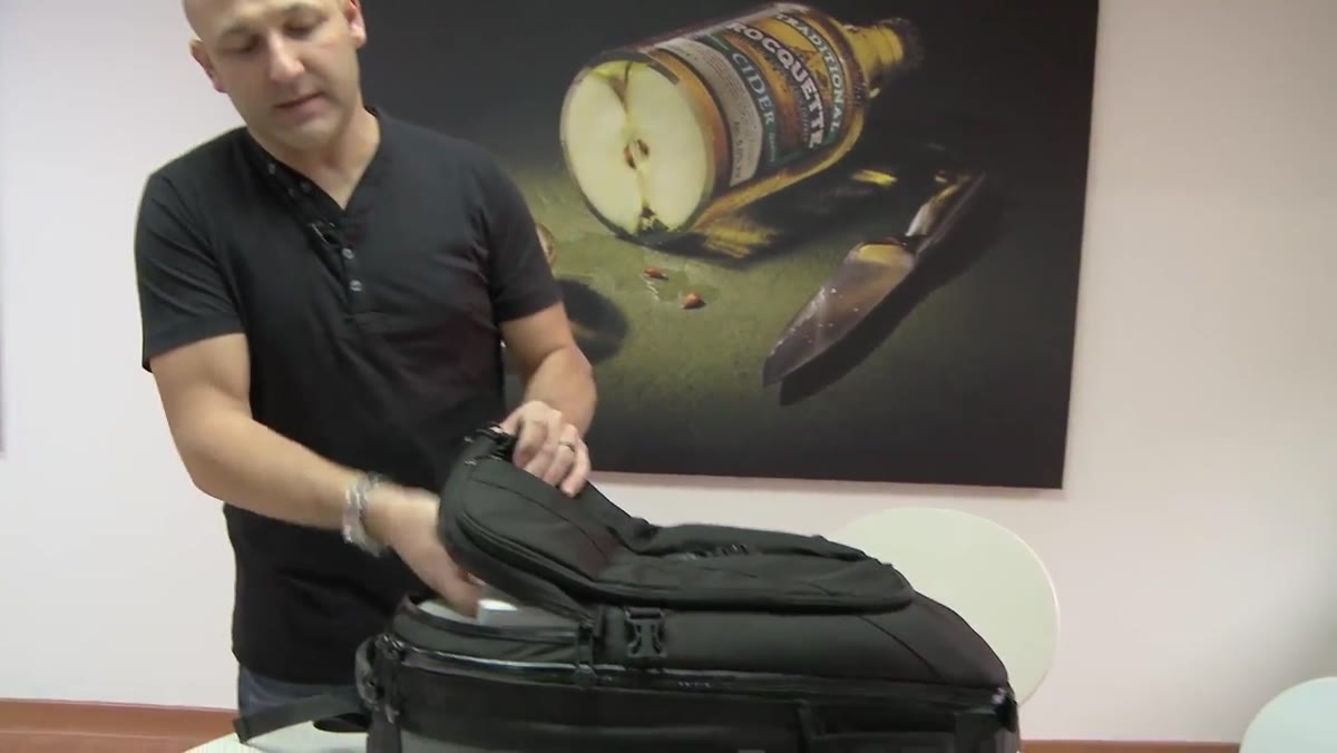 Laptop being slid into the rear zip pocket of the camera bag