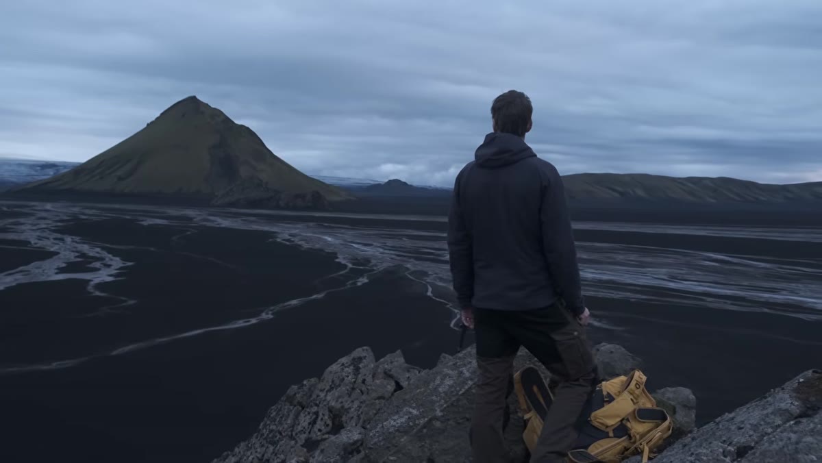 Heaton hiking up rocky peak above the black sand desert