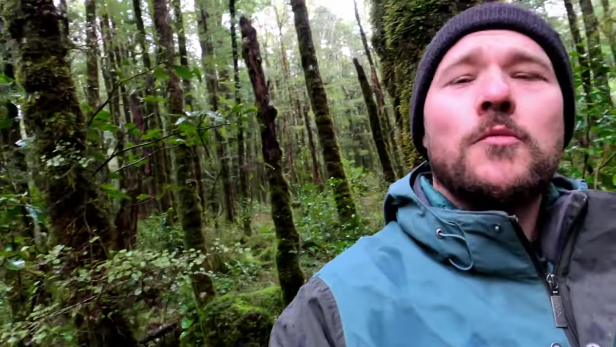 Photographer adjusting zoom on mid-range lens in forest setting