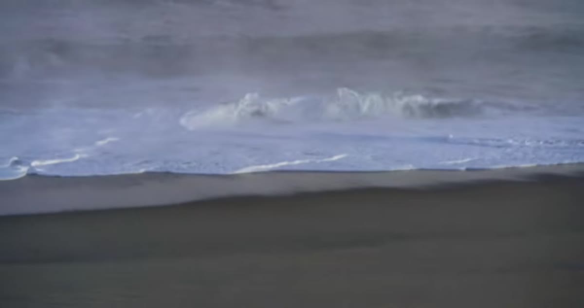 Whitewash rolling up the shoreline during panning motion