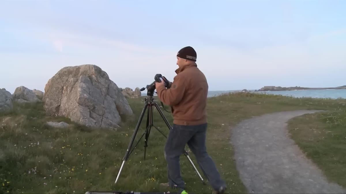 Photographer framing an outdoor stone scene at night
