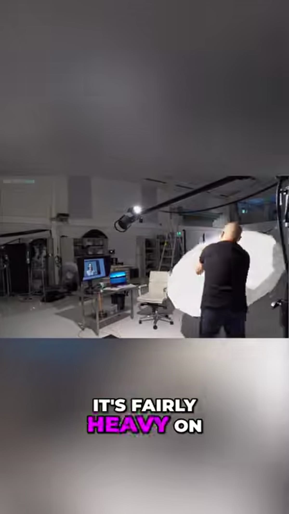 Large white umbrella mounted on light stand, visibly bowing