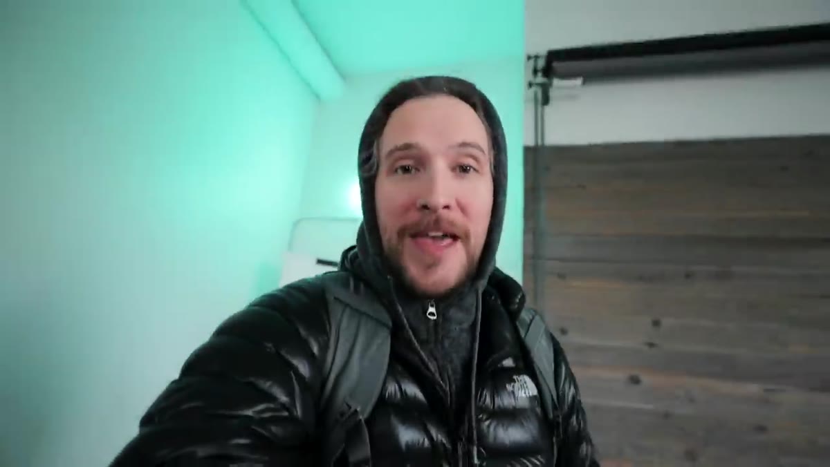 Peter walking into studio holding camera, appearing to film himself