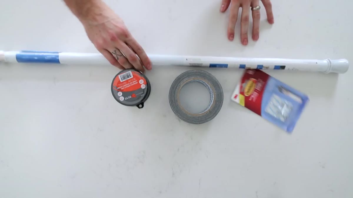 Tape, fishing line, command hooks, and bathtub rod laid out