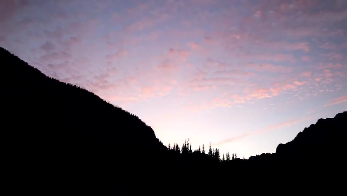 High-altitude clouds catching early color above the mountain