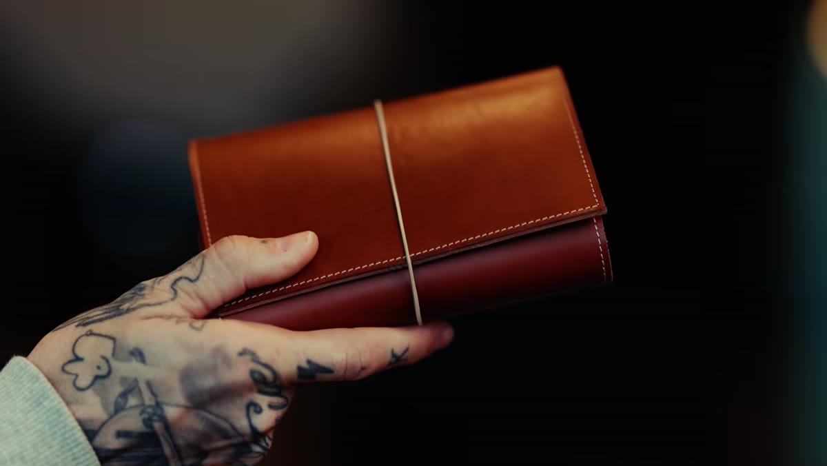 Peter holding open a leather folio with inserts visible