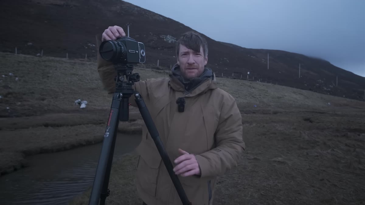 Thomas at waist level with Hasselblad, adjusting composition on salt marshes