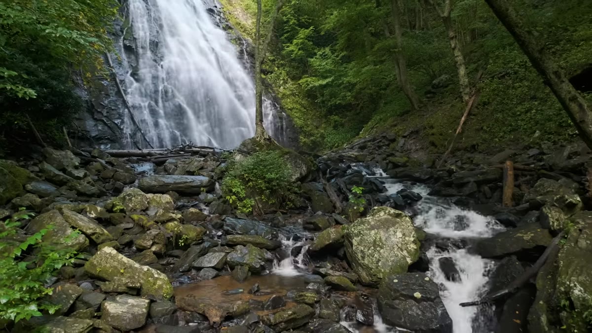 Photographer positioning camera close to foreground rocks near waterfall